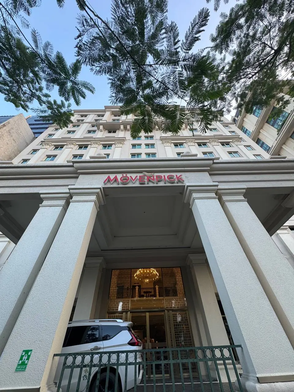 나무 아래에서 올려다본 뫼뵌픽 호텔 정면과 붉은색 Movenpick 간판