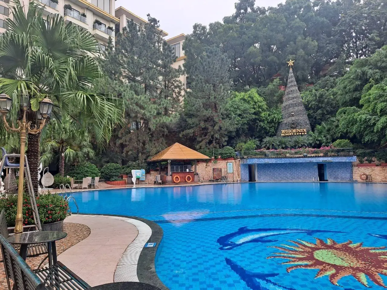 PHOENIX RESORT 표지와 녹지가 둘러싼 야외 수영장